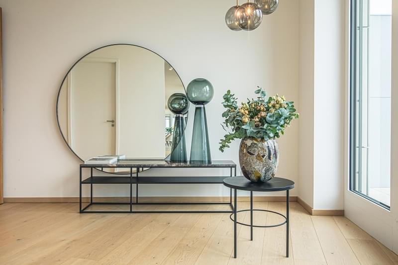 Ein modernes Innendesign eines Wohnraums im Innenbereich mit einem Tisch, einer Vase und Dekor auf dem Boden einer Wohnung.